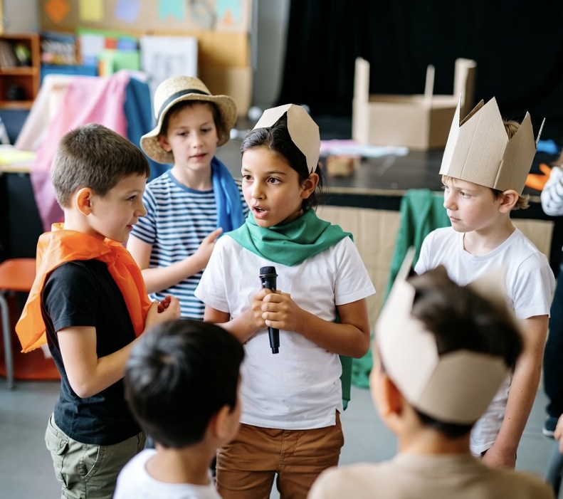 A group of children engaging in a drama activity in a school classroom setting
